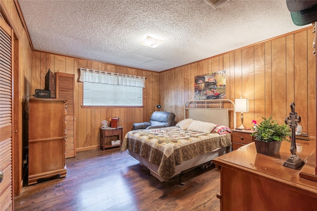 bedroom featuring dark wood-type flooring, wooden walls, and a textured ceiling