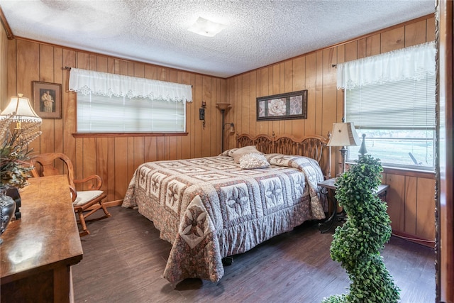 bedroom featuring a textured ceiling, dark hardwood / wood-style flooring, and wood walls