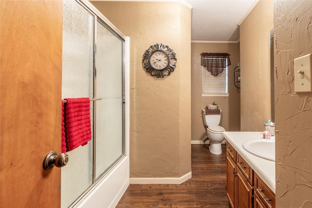 full bathroom featuring combined bath / shower with glass door, hardwood / wood-style floors, vanity, toilet, and a textured ceiling