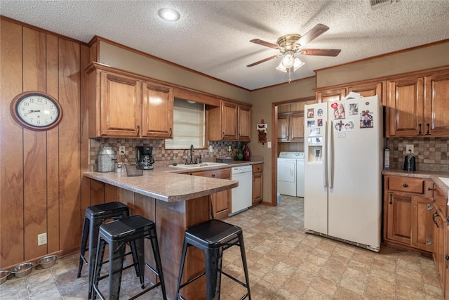 kitchen featuring sink, crown molding, white appliances, a breakfast bar area, and kitchen peninsula