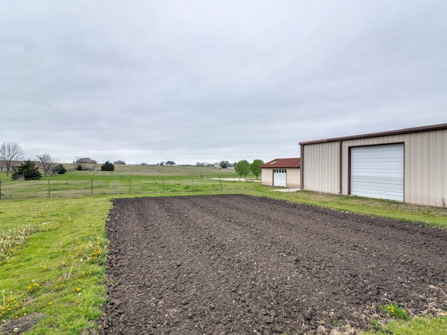 view of yard featuring a rural view, a garage, and an outdoor structure