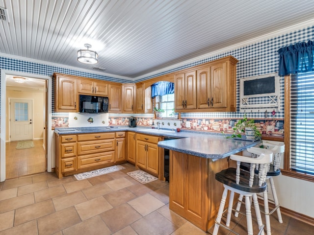 kitchen with a breakfast bar, sink, ornamental molding, and backsplash