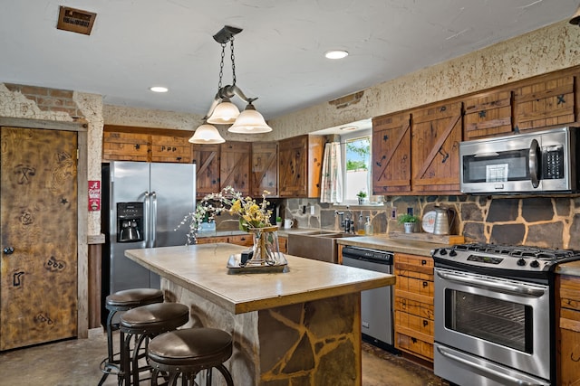 kitchen featuring sink, decorative backsplash, appliances with stainless steel finishes, decorative light fixtures, and a kitchen island