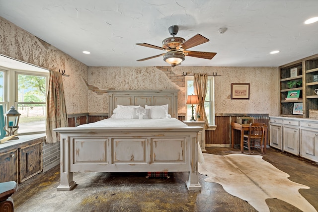 bedroom with ceiling fan and wooden walls