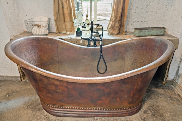 room details with a tub to relax in, sink, and concrete floors