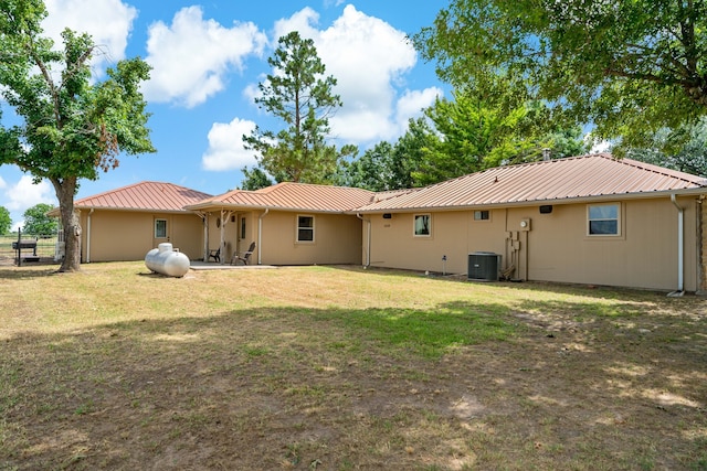 back of house with central AC and a lawn