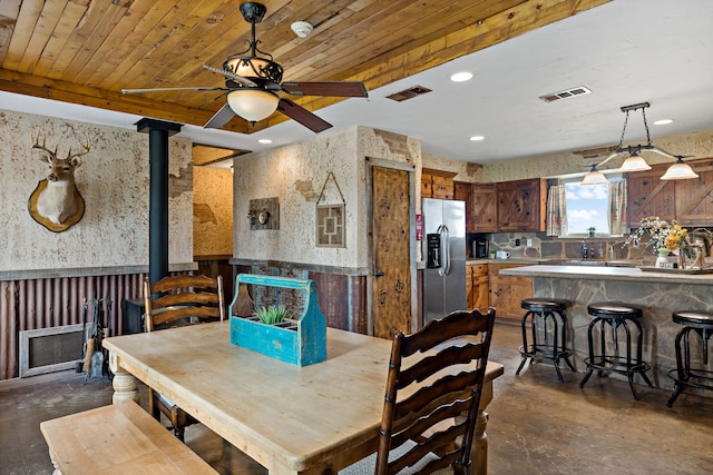 dining room with a wood stove, ceiling fan, and wooden ceiling