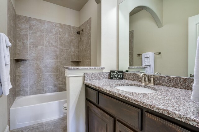 full bathroom with tile patterned floors, vanity, tiled shower / bath combo, and toilet