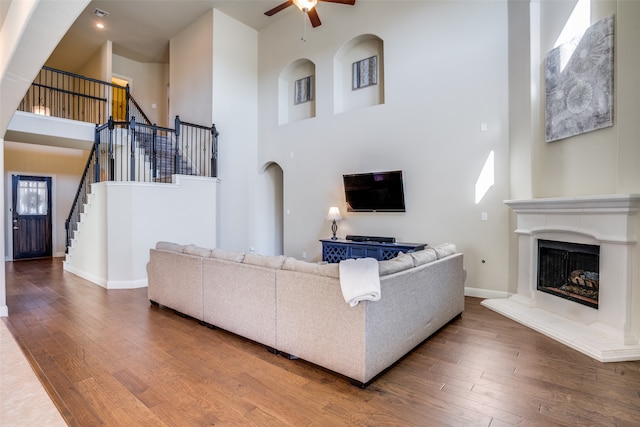 living room featuring a towering ceiling, hardwood / wood-style flooring, and ceiling fan