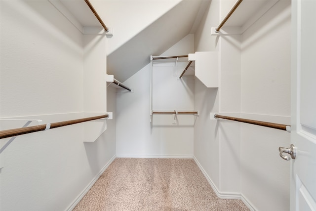 walk in closet featuring light colored carpet and lofted ceiling