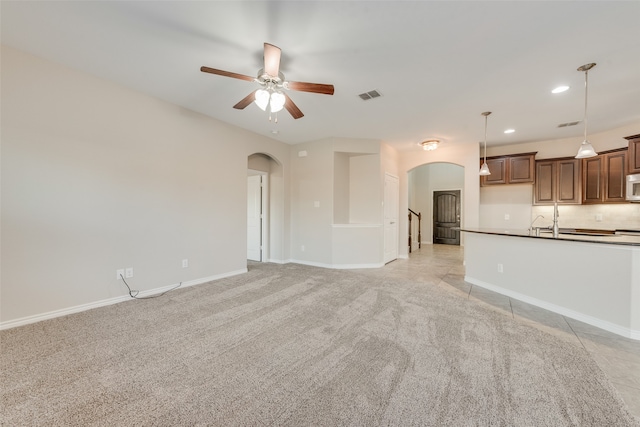 unfurnished living room featuring light carpet and ceiling fan