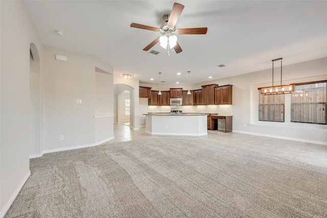 unfurnished living room featuring light carpet, a wealth of natural light, and ceiling fan