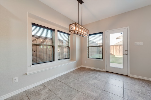 unfurnished dining area featuring an inviting chandelier, plenty of natural light, and light tile patterned flooring