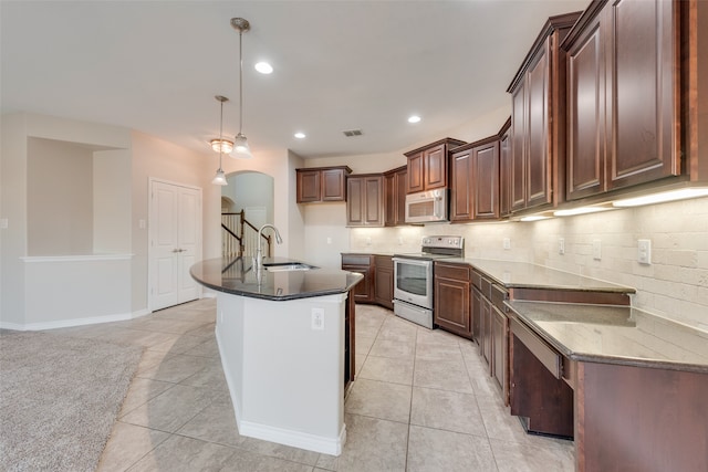 kitchen featuring decorative backsplash, a kitchen island with sink, sink, electric stove, and hanging light fixtures