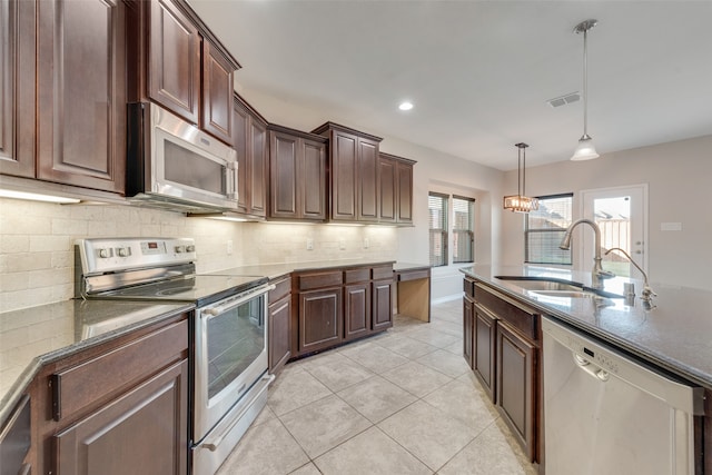 kitchen featuring pendant lighting, sink, light tile patterned floors, appliances with stainless steel finishes, and tasteful backsplash