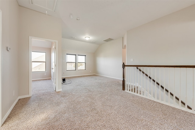 carpeted spare room with vaulted ceiling