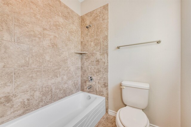 bathroom featuring tile patterned flooring, tiled shower / bath combo, and toilet