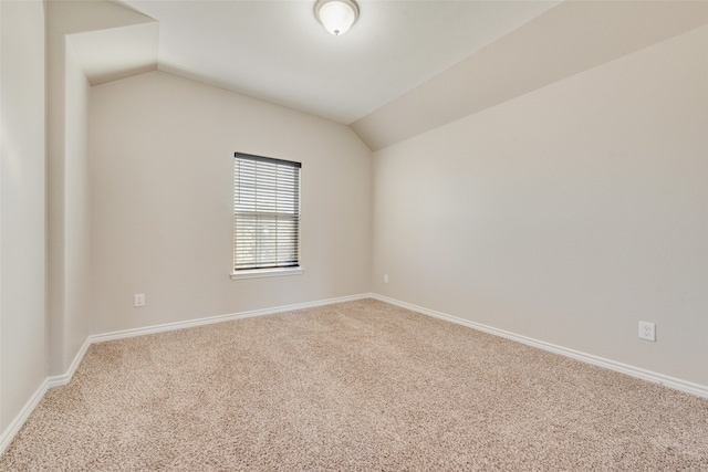 carpeted spare room with vaulted ceiling