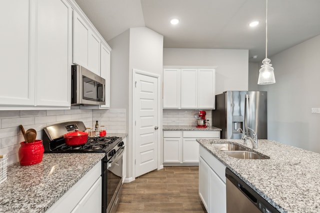 kitchen with tasteful backsplash, stainless steel appliances, sink, hardwood / wood-style flooring, and white cabinets