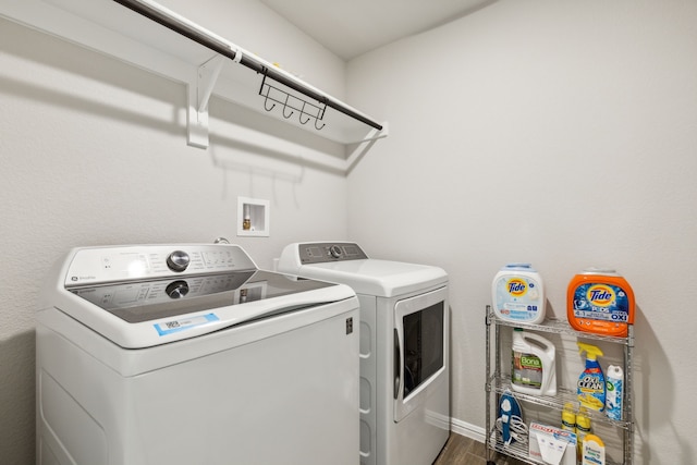 washroom with washing machine and clothes dryer and dark hardwood / wood-style floors