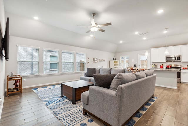 living room with light hardwood / wood-style floors, lofted ceiling, and a wealth of natural light