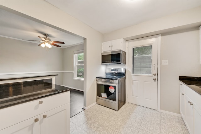 kitchen featuring white cabinets, ceiling fan, ornamental molding, light tile patterned floors, and stainless steel appliances