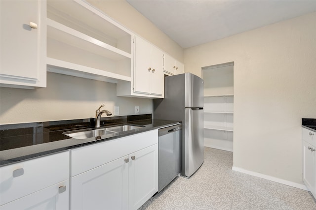 kitchen featuring white cabinetry, stainless steel dishwasher, dark stone counters, and sink