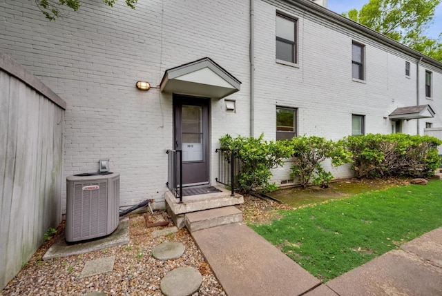 doorway to property featuring cooling unit and a lawn