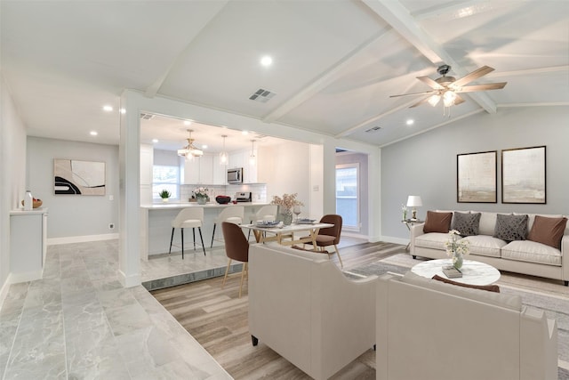 living room with lofted ceiling with beams and ceiling fan with notable chandelier