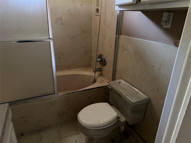 bathroom with toilet and bath / shower combo with glass door