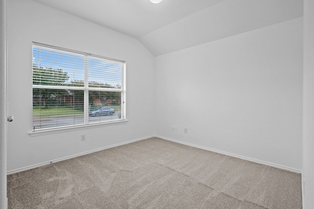 carpeted empty room featuring lofted ceiling