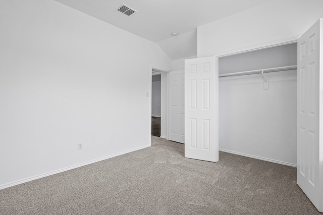 unfurnished bedroom featuring carpet, a closet, and vaulted ceiling