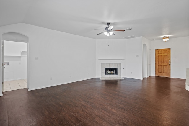 unfurnished living room with a tile fireplace, ceiling fan, dark hardwood / wood-style flooring, and vaulted ceiling