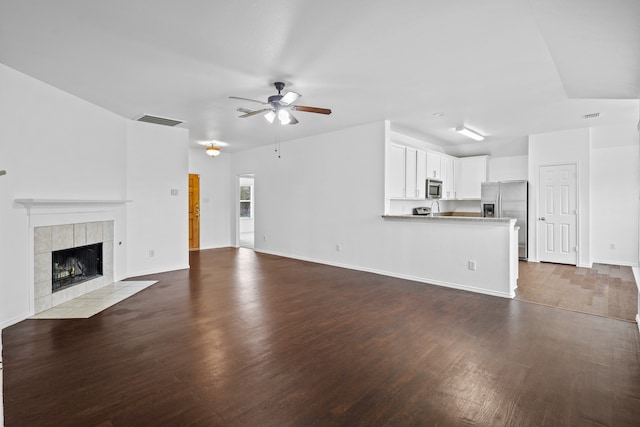 unfurnished living room with ceiling fan, dark hardwood / wood-style flooring, and a fireplace