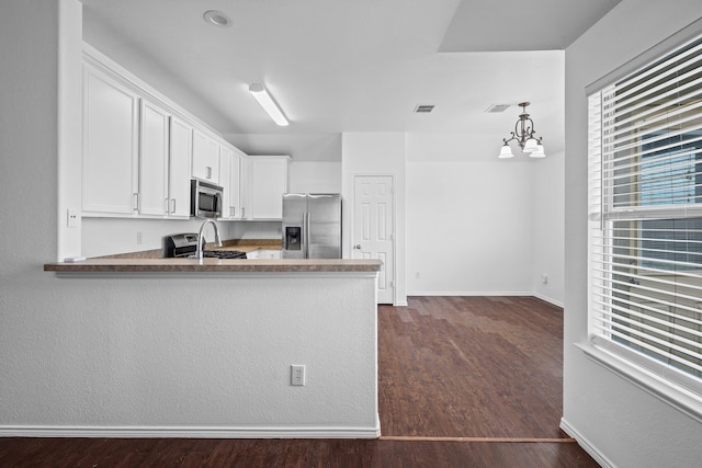 kitchen featuring white cabinetry, hanging light fixtures, dark wood-type flooring, stainless steel appliances, and kitchen peninsula