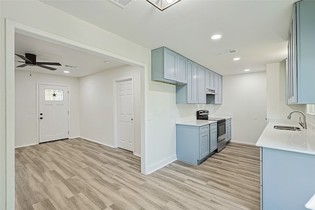 kitchen featuring electric range, ceiling fan, light wood-type flooring, and sink