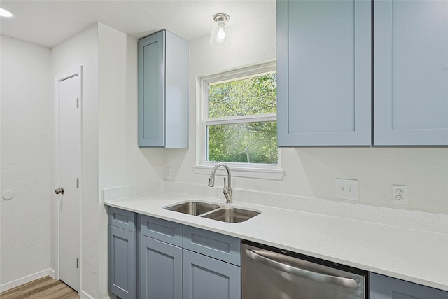 kitchen featuring hardwood / wood-style floors, dishwasher, light stone counters, and sink