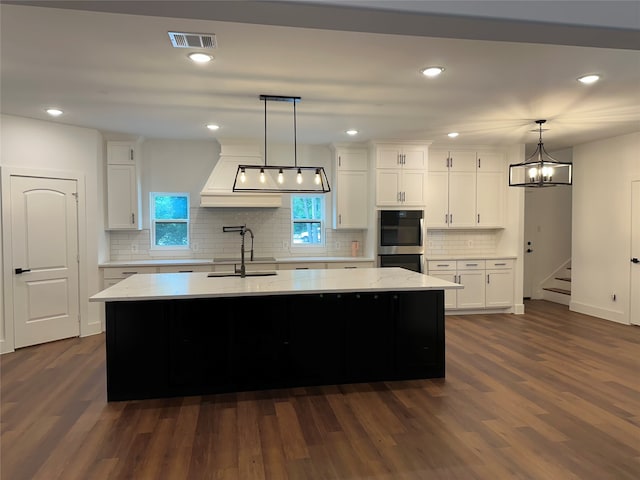 kitchen with dark hardwood / wood-style flooring, a center island with sink, and white cabinetry