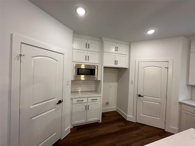 kitchen featuring backsplash, white cabinetry, stainless steel microwave, and dark hardwood / wood-style floors