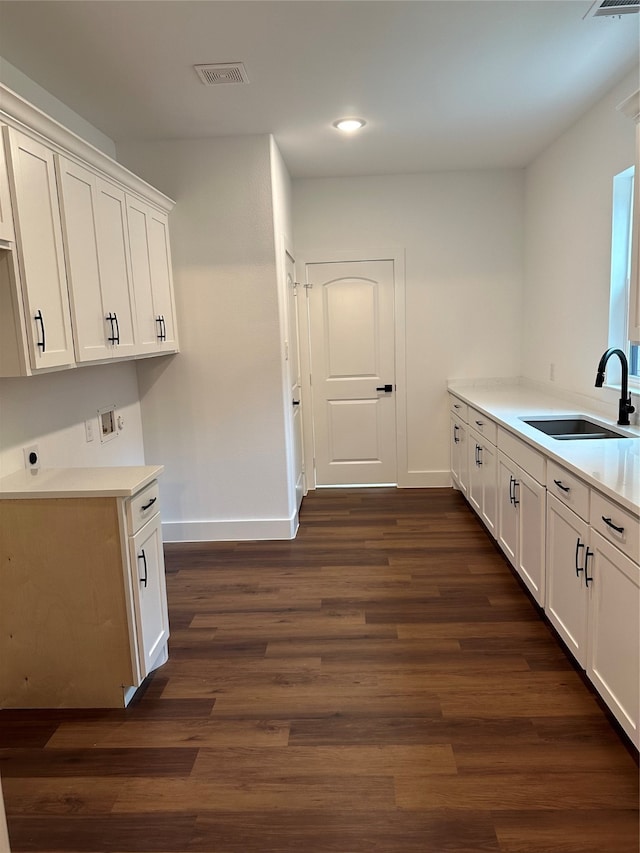 kitchen with dark hardwood / wood-style flooring, white cabinetry, and sink