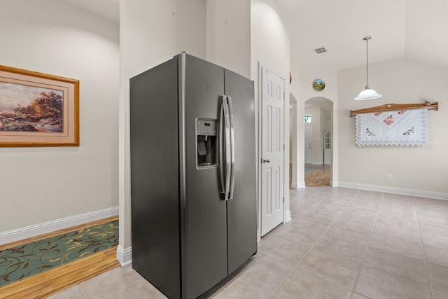 kitchen with decorative light fixtures, stainless steel fridge with ice dispenser, light tile patterned floors, and vaulted ceiling