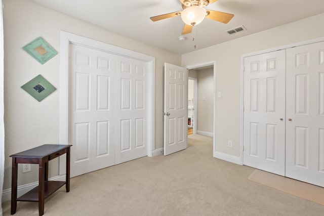 carpeted bedroom featuring ceiling fan and multiple closets