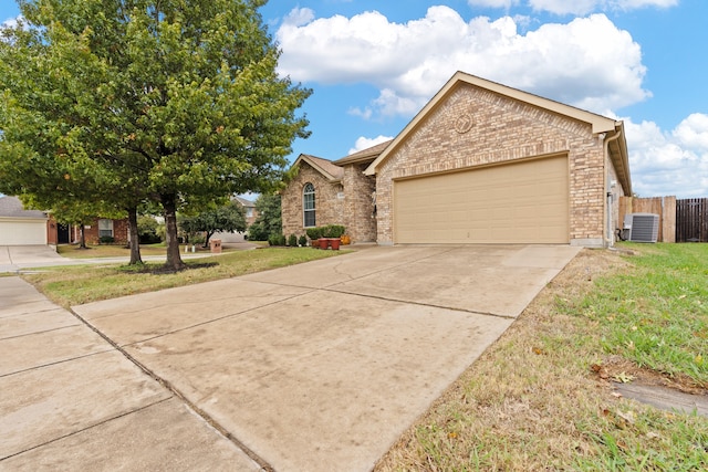 view of front of house with a garage, central air condition unit, and a front yard