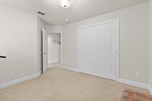 unfurnished bedroom featuring light carpet and a closet