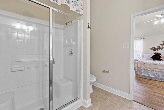 bathroom featuring wood-type flooring, toilet, ceiling fan, and a shower with shower door