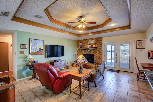 living room featuring french doors, a textured ceiling, light tile patterned floors, a raised ceiling, and a fireplace