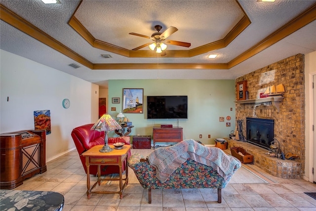 tiled living room featuring a raised ceiling, ornamental molding, ceiling fan, and a textured ceiling