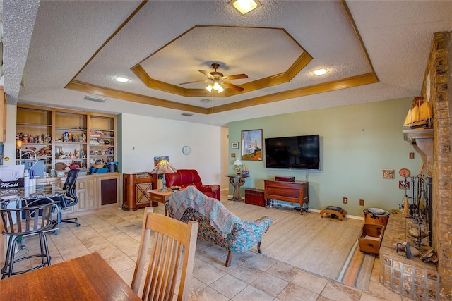 living room with light tile patterned floors, ceiling fan, a textured ceiling, built in shelves, and a raised ceiling