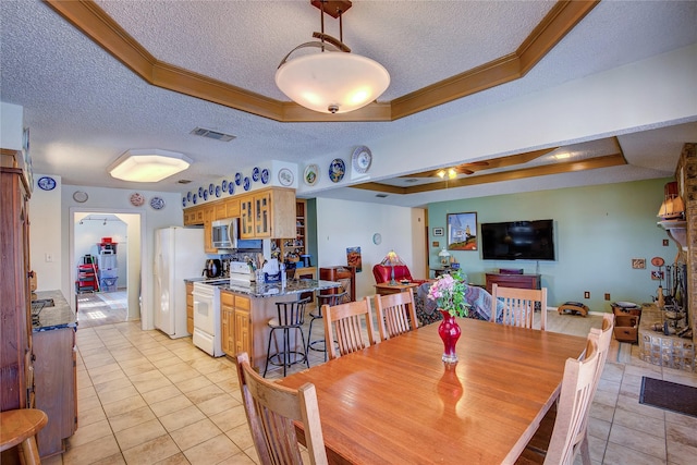 dining room featuring a raised ceiling, light tile patterned flooring, a textured ceiling, and crown molding