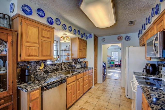 kitchen with appliances with stainless steel finishes, sink, light tile patterned floors, and a textured ceiling